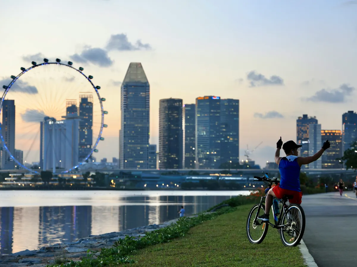 A cyclist beside Marina Bay with the Singapore Flyer and city skyline behind